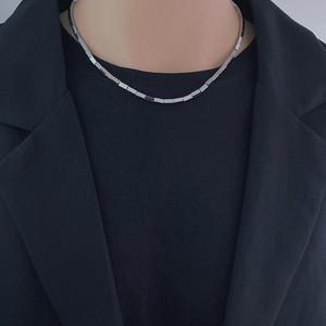 Close-up of geometric cube chain necklace in polished steel on a model with black suit