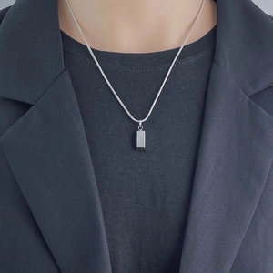 Collana con pendente rettangolare in argento lucido per uomo e donna su abito nero