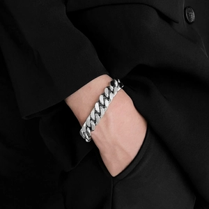 Primo piano di un bracciale a catena cubana argento indossato con una giacca nera