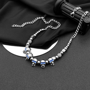 Détail d'un collier gothique en argent avec crânes aux yeux bleus et perles en métal