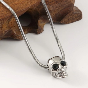 Punk style skull pendant necklace with black gems on a silver steel snake chain