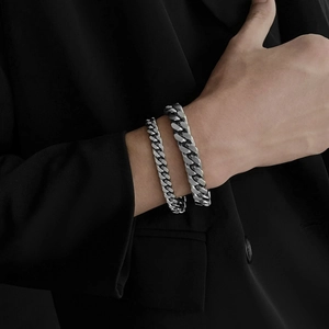 Dettaglio di bracciali a maglia cubana in argento spessi e sottili su abito nero
