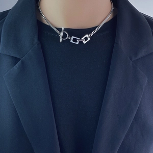 Detail of silver titanium steel necklace with toggle clasp on person with black clothing