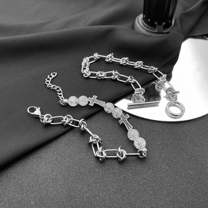 Détail du bracelet chaîne en acier titane avec perles dépolies et pendentifs croix