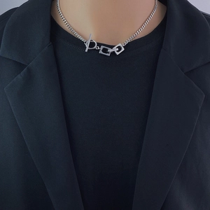 Close-up of unisex silver titanium steel necklace with OT buckle and geometric charms