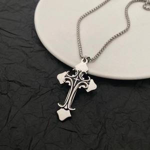 Dettaglio del ciondolo a croce gotica argento con intarsio nero e catena in acciaio