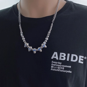 Détail macro du collier hip-hop avec crânes aux yeux bleus et perles d'acier mixtes