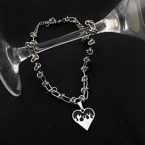 Macro detail of silver heart necklace with black flame pattern on bold metal chain