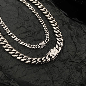 Colliers à mailles gourmette avec fermoir texturé diamant sur fond noir froissé