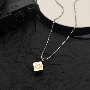 Detail of silver stainless steel box chain with yellow smiley face dice pendant