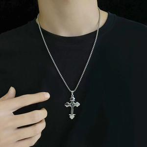 Dettaglio di un ciondolo a croce gotica in argento con motivi barocchi su una catena