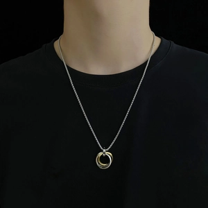 Détail du pendentif homme à trois anneaux entrelacés or et argent sur chaîne box
