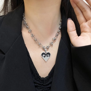 Detail of silver chain necklace with a black flame heart pendant on a black suit blazer