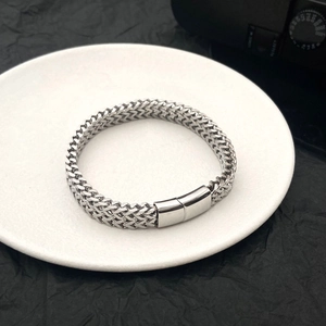 Macro shot of polished silver wheat chain bracelet showing intricate metal weaving detail