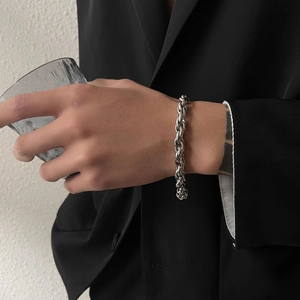 Gros plan d'un bracelet gourmette en argent poli porté en tenant un verre givré