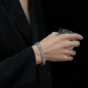 Detail of multi-layer stainless steel woven bracelet on male model wearing black suit