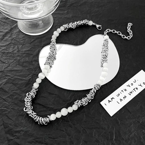 Detailed shot of cat eye stone and metal spiral beaded necklace on textured black paper