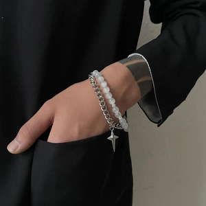 Detail of double-layer Cuban chain and white cat eye stone bead bracelet with star charm