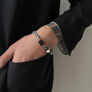 Asymmetric black and white beaded bracelet with rectangular gemstone on model wrist