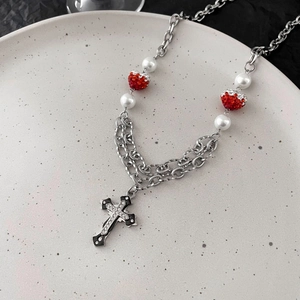 Makroansicht der Schicht-Halskette mit Kreuz, roten Herzanhängern und weißen Perlen