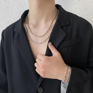 Detail of silver double-layered Möbius chain and matching bracelet on a black suit