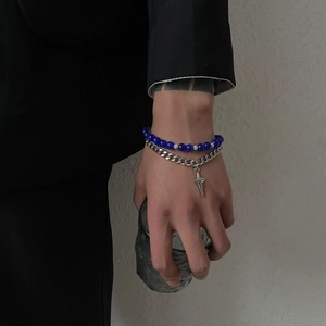 Close-up of double-layer bracelet with blue beads, silver cuban chain and star pendant