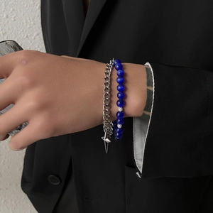 Close-up of minimalist layered cuban link and blue bead bracelets on a wrist