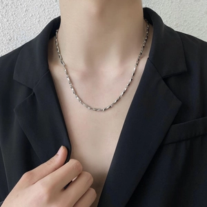Minimalist silver stainless steel curb chain necklace worn by a male model in a suit