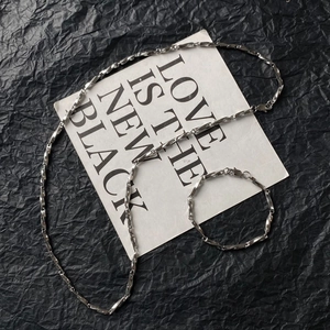 Close-up of silver titanium steel chain jewelry set with flat twisted geometric links