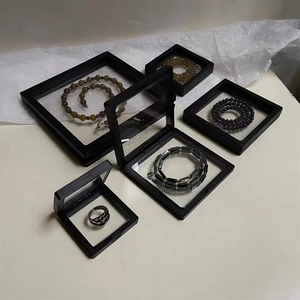 Suspension jewelry boxes with black frames showing necklaces and rings in floating film