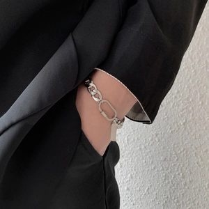 Detail of silver cuban link bracelet featuring a carabiner ring and polished rectangular tag