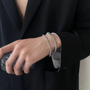 Détail d'un bracelet double couche en acier inoxydable argenté porté avec accessoire