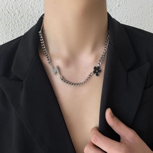 Collier hip hop argenté avec pendentifs éclair et fleur noire porté par un mannequin