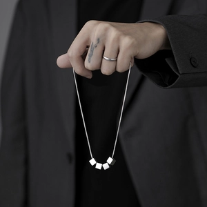 Gros plan d'un collier minimaliste en acier titane avec cinq pendentifs cubes géométriques