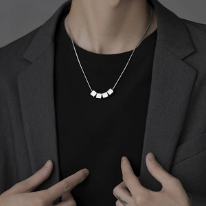Détail d'un collier en acier titane argenté avec quatre pendentifs cubes géométriques