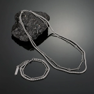 Close-up of double-layered silver titanium steel bamboo chain necklace on black stone
