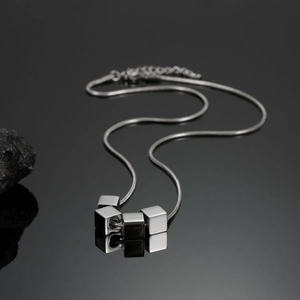 Pendentif cube poli en argent sur chaîne serpent avec fond de pierre noire élégante