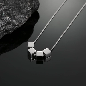 Détail macro du pendentif cube géométrique sur une chaîne serpent en acier inoxydable