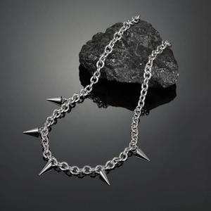Macro detail of punk silver spike necklace with polished ring chain on black stone