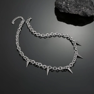 Detail of silver punk spike necklace with five conical pendants on black mirror surface