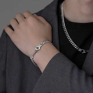 Detail view of silver curb chain set with textured round lock on a male model