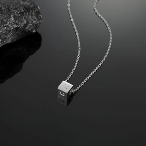 Macro detail of cube pendant with smile face engravings on high-gloss black surface