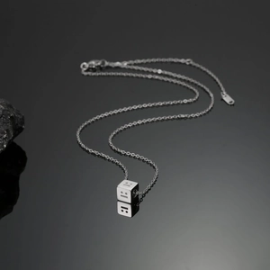 Detailed close-up of a silver cube pendant featuring minimalist engraved emotion faces