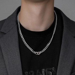 Detail of silver Cuban chain necklace with interlocking handcuff clasp on a male model
