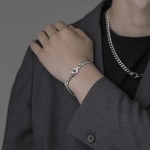 Men's silver Cuban chain necklace and bracelet set with G-shaped buckle on gray suit