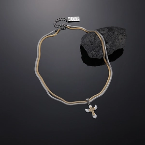 Detail of two-tone snake chain necklace with winged cross pendant and love tag
