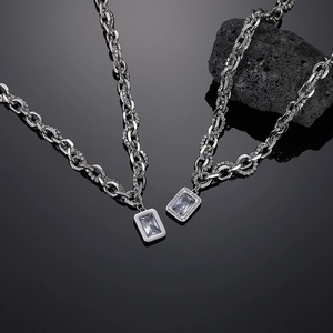 Close-up of silver chain necklace with rectangle zircon pendant on volcanic rock