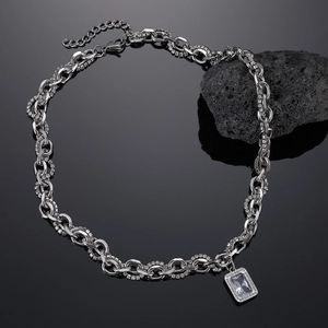Detailed close-up of a silver cuban chain necklace with a rectangle crystal pendant