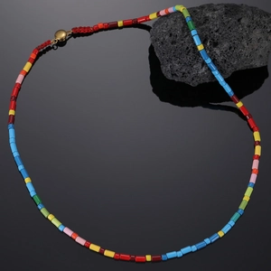 Macro detail of colorful cylindrical beads and golden metallic clasp on bohemian necklace