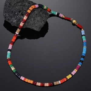Macro shot of multi-colored beaded necklace with gold clasp on black volcanic stone